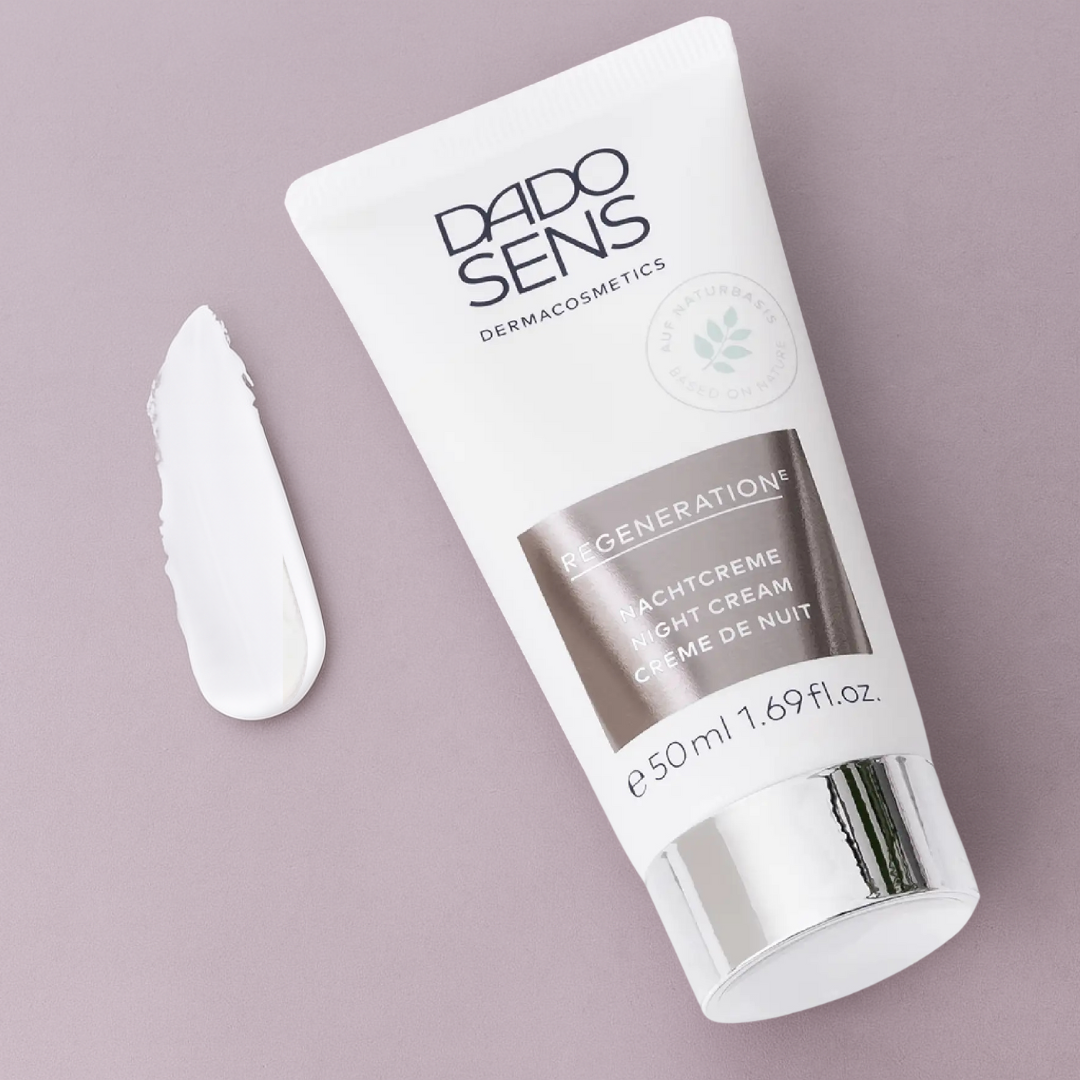DADO SENS REGENERATION E Nachtcreme 50 ml – stilvolle Produktaufnahme mit Creme-Swatch auf fliederfarbenem Hintergrund