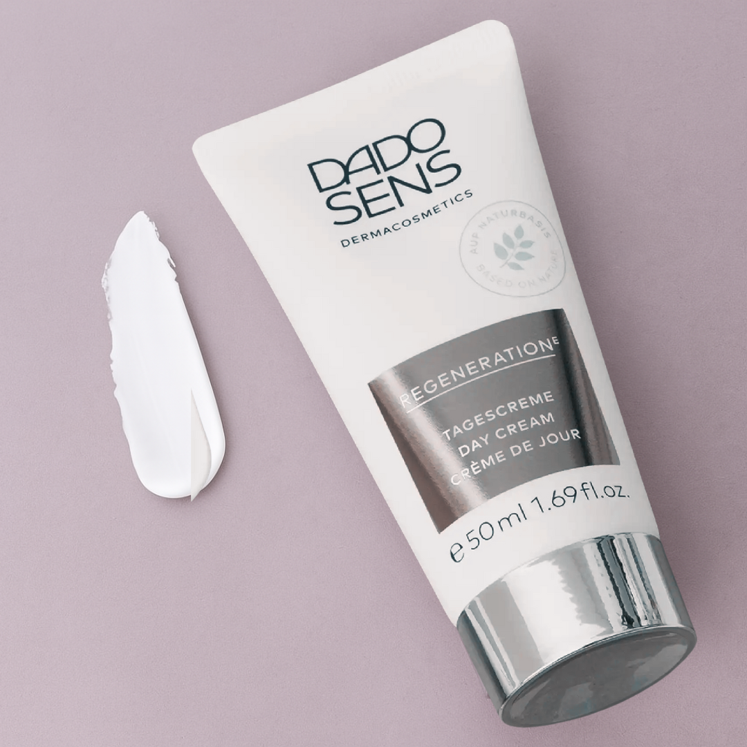DADO SENS REGENERATION E Tagescreme 50 ml – Moodbild der Tube mit sichtbarer Creme-Textur auf fliederfarbenem Untergrund