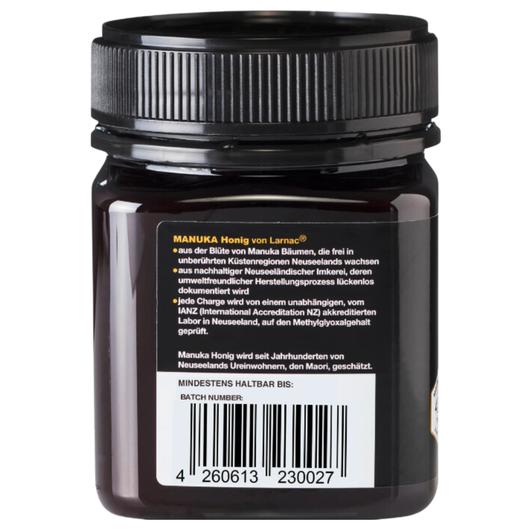 Rückseite eines Glases Larnac Manuka Honig mit schwarzem Deckel. Das Etikett beschreibt, dass der Honig aus der Blüte von Manuka Bäumen stammt, die in unberührten Küstenregionen Neuseelands wachsen. Es wird darauf hingewiesen, dass der Honig aus nachhaltiger neuseeländischer Imkerei stammt, deren umweltfreundlicher Herstellungsprozess lückenlos dokumentiert wird. Jede Charge wird in einem unabhängigen, akkreditierten Labor auf Methylglyoxalgehalt geprüft.