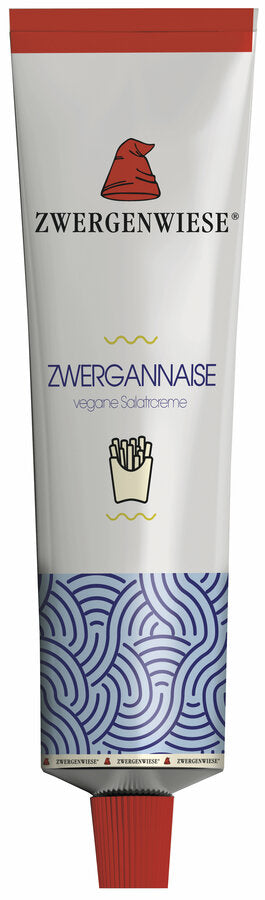 Eine Tube mit der veganen Salatcreme "Zwergannaise" von der Marke Zwergenwiese. Das Etikett zeigt eine rote Zwergenmütze und die Aufschrift "Zwergannaise - vegane Salatcreme". Am unteren Rand der Tube befindet sich ein blaues, wellenförmiges Muster. Die Tube hat einen roten Verschluss. Eine kleine Abbildung von Pommes Frites unterstreicht die vielseitige Verwendbarkeit der Creme als Dip.