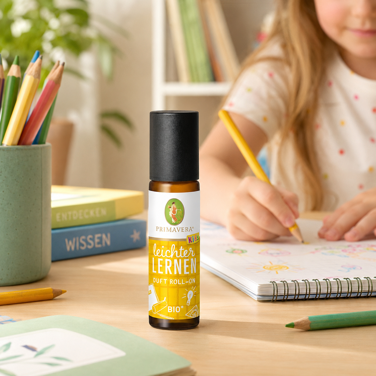 PRIMAVERA Leichter lernen Duft Roll-On auf einem Schreibtisch neben einem Kind beim Malen und Lernen