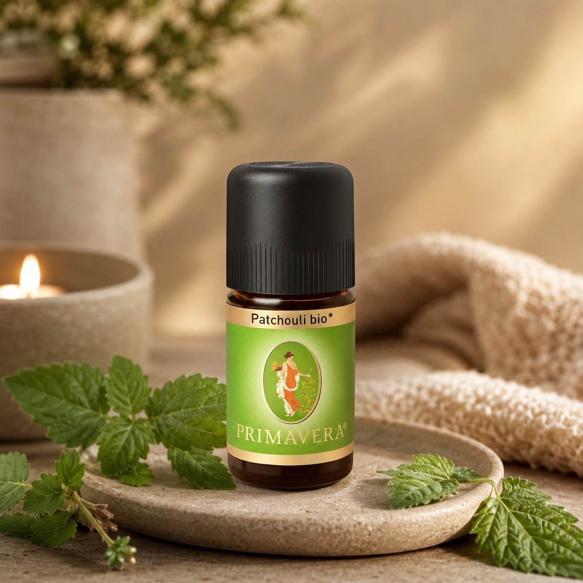 PRIMAVERA Patchouli bio ätherisches Öl in einer natürlichen Wellness-Szene mit grünen Patchouli-Blättern