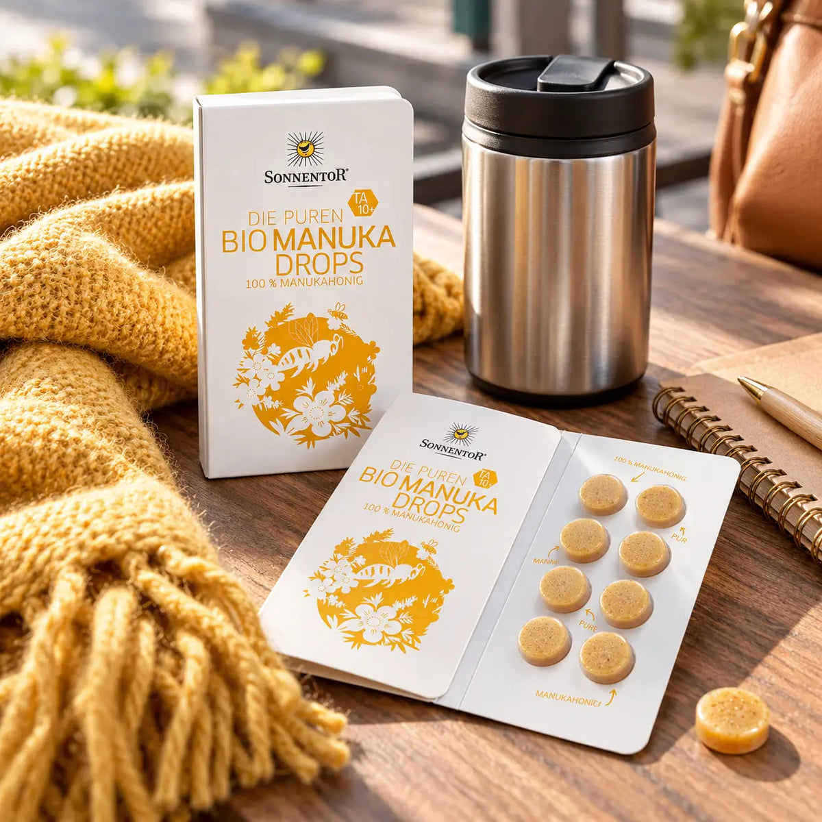 Sonnentor Bio Manuka Drops unterwegs neben Thermobecher und geöffnetem Drop-Pack