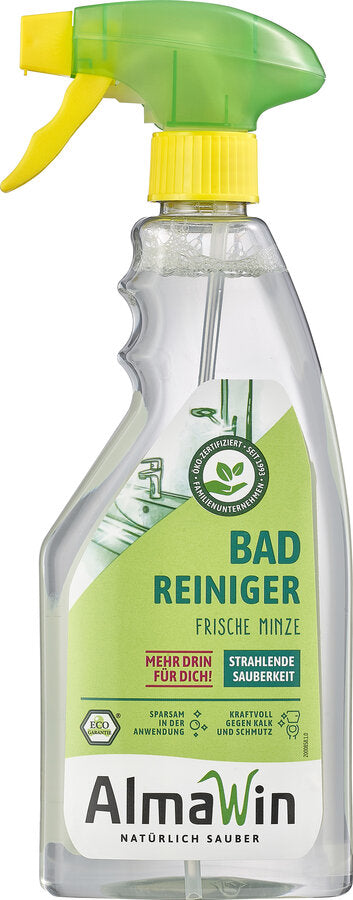 Produktbild einer Sprühflasche AlmaWin Badreiniger mit frischer Minze. Die Flasche besitzt einen grünen Sprühkopf mit gelbem Hebel, ein transparentes Gehäuse und ein grün-weißes Etikett mit der Aufschrift 'Bad Reiniger Frische Minze'. Weitere Hinweise auf dem Etikett betonen die ökologische Zertifizierung, kraftvolle Reinigung gegen Kalk und Schmutz sowie sparsame Anwendung.