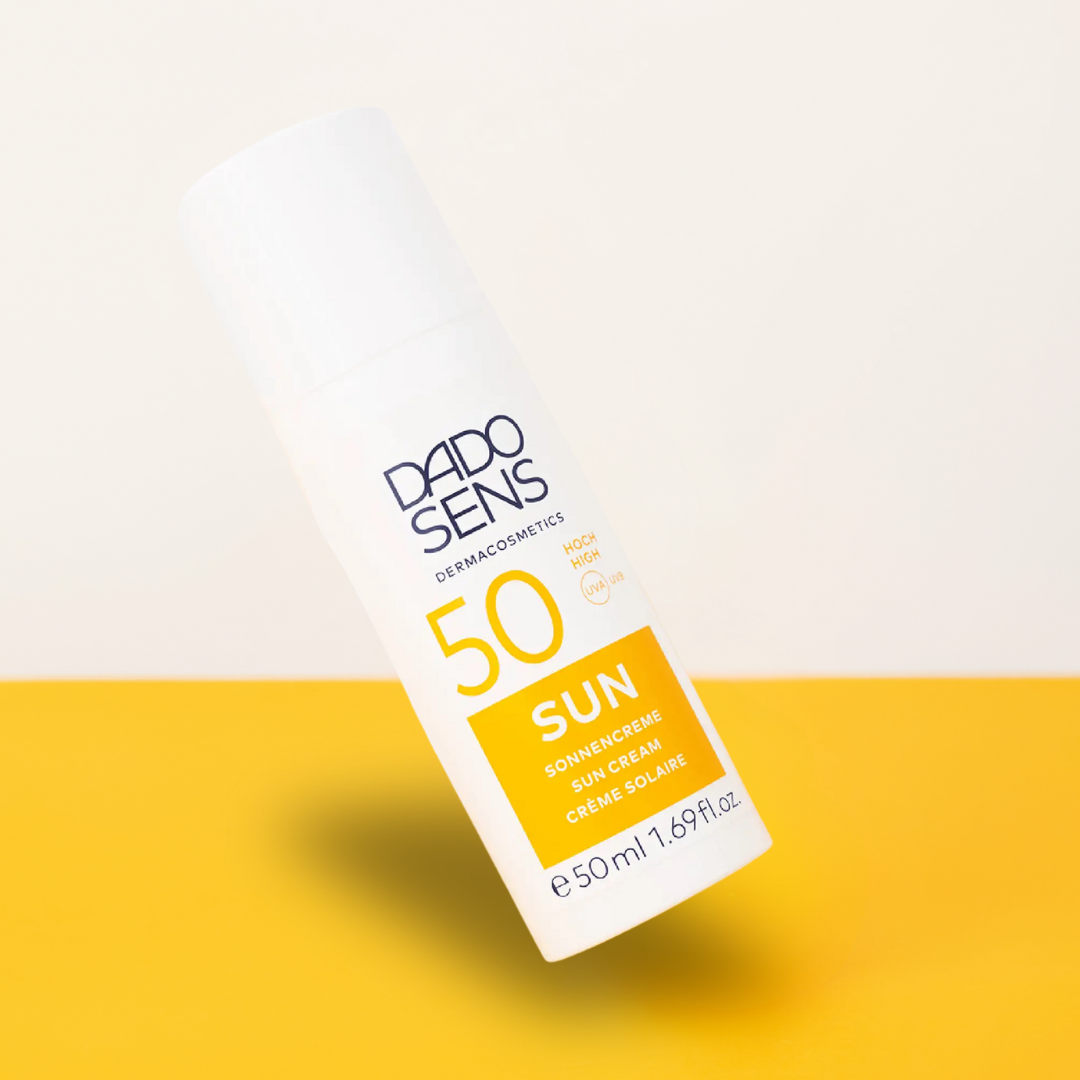 DADO SENS Sonnencreme LSF 50 – Produktfoto auf gelbem Untergrund, Spender in Schräglage, Sonnenschutz für empfindliche Haut

