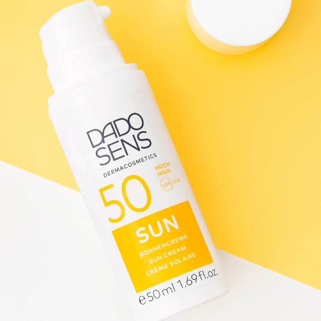 DADO SENS Sonnencreme LSF 50 – geöffnete Spenderflasche auf gelb-weißem Hintergrund, cremige Textur sichtbar