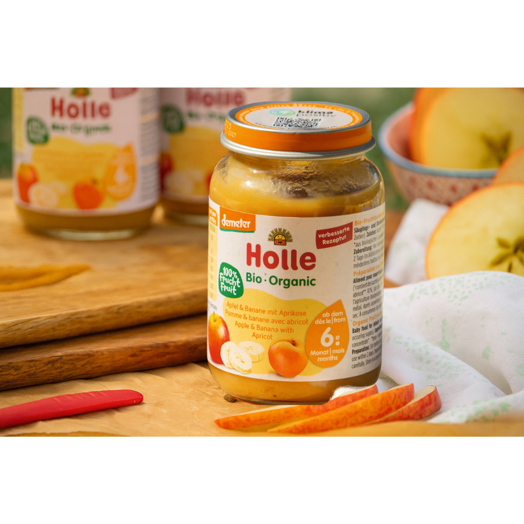 Stimmungsbild mit Holle Bio-Babygläschen Apfel & Banane mit Aprikose – umgeben von frischen Apfelscheiben – ab dem 6. Monat