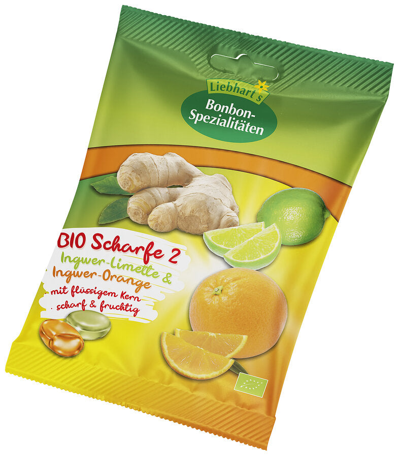 Das Bild zeigt eine gelb-grüne Verpackung der Marke Liebhart's Bonbon-Spezialitäten. Auf der Vorderseite der Verpackung sind Ingwer, Limetten und Orangen abgebildet. Der Produktname "BIO Scharfe 2" ist in roter Schrift zu lesen, darunter die Geschmacksrichtungen "Ingwer-Limette & Ingwer-Orange" in weißer Schrift auf grünem Hintergrund. Darunter steht "mit flüssigem Kern scharf & fruchtig". Links unten befinden sich zwei Bonbons in den Farben grün und orange, daneben ein Bio-Siegel.