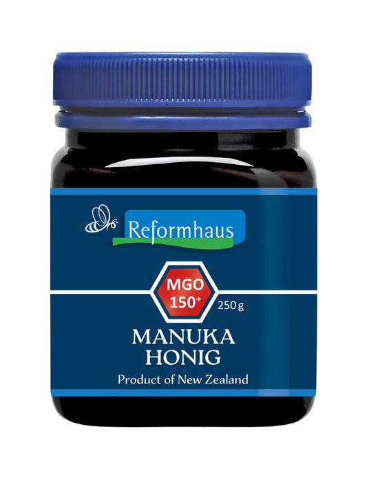 Ein Glas Reformhaus Manuka Honig MGO 150+ aus Neuseeland mit einem blauen Deckel. Das Etikett zeigt das Reformhaus-Logo, die Aufschrift "MGO 150+", und "250 g". Manuka Honig ist bekannt für seine antibakteriellen Eigenschaften und wird häufig zur Unterstützung des Immunsystems und der allgemeinen Gesundheit verwendet