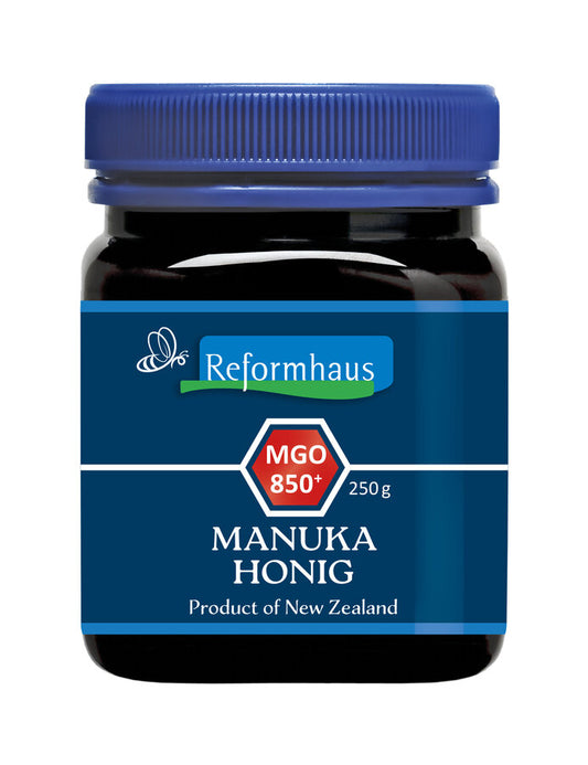 Ein Glas Reformhaus Manuka Honig MGO 850+ aus Neuseeland mit einem blauen Deckel. Das Etikett zeigt das Reformhaus-Logo, die Aufschrift "MGO 850+", und "250 g". Dieser Honig hat einen sehr hohen MGO-Gehalt, was auf besonders starke antibakterielle Eigenschaften hinweist und ihn ideal für den gezielten Einsatz zur Unterstützung der Gesundheit und Immunfunktion macht.