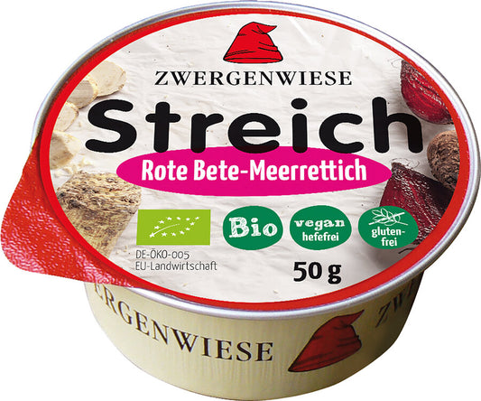 Das Bild zeigt eine runde Dose des veganen Brotaufstrichs "Streich Rote Bete-Meerrettich" von Zwergenwiese. Die Dose hat einen roten Deckelrand und eine weiße Oberseite mit der Aufschrift "Zwergenwiese Streich Rote Bete-Meerrettich". Es gibt Symbole, die das Produkt als bio, vegan (hefefrei) und glutenfrei kennzeichnen. Die Nettofüllmenge beträgt 50 Gramm. Auf dem Deckel sind außerdem Abbildungen von Roter Bete und Meerrettich zu sehen.