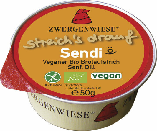 Das Bild zeigt eine runde, vegane Brotaufstrich-Dose der Marke Zwergenwiese. Die Dose hat einen roten Deckelrand und eine orangefarbene Oberseite mit der Aufschrift "streich's drauf Sendi". Unterhalb des Produktnamens steht "Veganer Bio Brotaufstrich Senf, Dill". Es gibt auch Symbole, die das Produkt als vegan und bio-zertifiziert kennzeichnen. Die Nettofüllmenge beträgt 50 Gramm. Das Markensymbol, ein roter Zwergenhut, ist ebenfalls auf dem Deckel abgebildet.