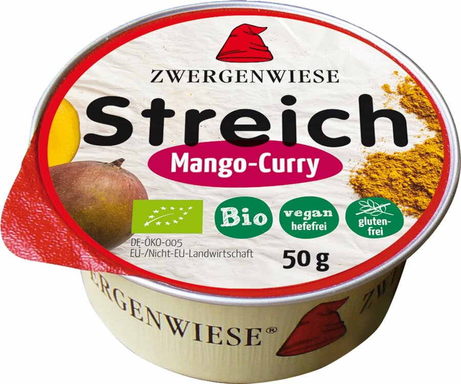 Das Bild zeigt eine runde Dose des veganen Brotaufstrichs "Streich Mango-Curry" von Zwergenwiese. Die Dose hat einen roten Deckelrand und eine weiße Oberseite mit der Aufschrift "Zwergenwiese Streich Mango-Curry". Es gibt Symbole, die das Produkt als bio, vegan (hefefrei) und glutenfrei kennzeichnen. Die Nettofüllmenge beträgt 50 Gramm. Auf dem Deckel sind außerdem Abbildungen einer Mango und von Currypulver zu sehen. Das Markensymbol, ein roter Zwergenhut, ist ebenfalls auf dem Deckel abgebildet.