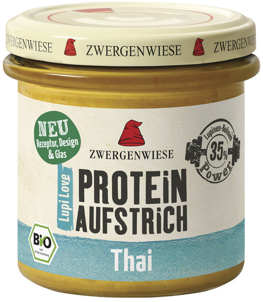 Das Bild zeigt ein Glas des veganen Proteinaufstrichs "Lupi Love Protein Aufstrich Thai" von Zwergenwiese. Der Deckel ist beige mit einem roten Zwergenhut. Das Etikett ist weiß und blau, mit der Aufschrift "PROTEIN AUFSTRICH Thai", "Bio" und einem Hinweis auf 35% Lupinen-Protein.