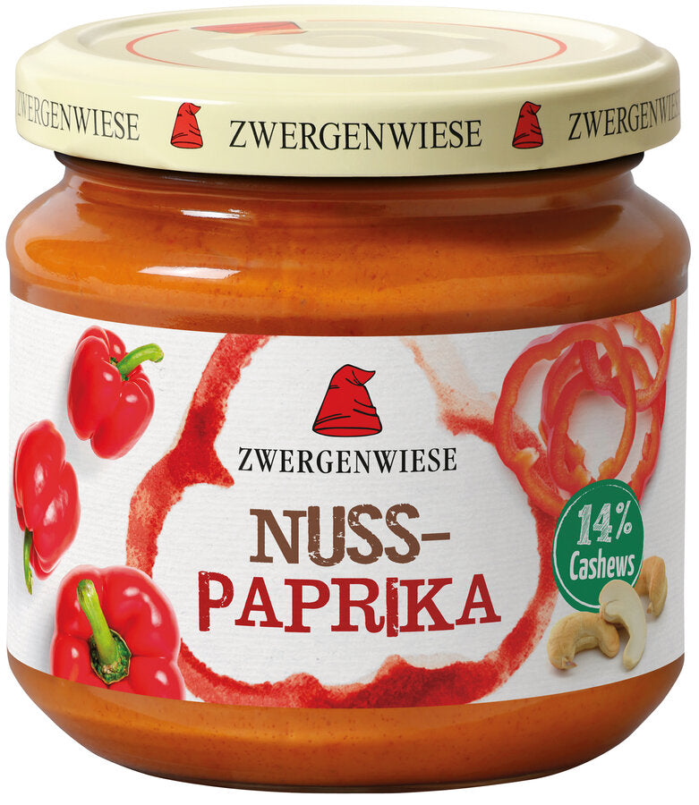 Das Bild zeigt ein Glas "Nuss-Paprika" von Zwergenwiese. Der Deckel ist beige mit einem roten Zwergenhut. Das Etikett ist weiß mit roten Paprikas und der Aufschrift "Zwergenwiese Nuss-Paprika". Rechts unten befindet sich ein grünes Siegel mit der Aufschrift "14% Cashews".