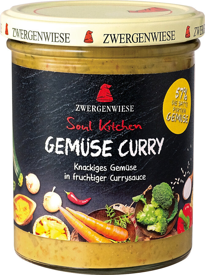 Das Bild zeigt ein Glas "Gemüse Curry" von Zwergenwiese aus der "Soul Kitchen" Reihe. Der Deckel ist beige mit einem roten Zwergenhut. Das Etikett ist schwarz und zeigt die Aufschrift "Zwergenwiese Soul Kitchen Gemüse Curry" in weißer und roter Schrift. Darunter steht "Knackiges Gemüse in fruchtiger Currysauce". Auf dem Etikett sind außerdem Abbildungen von Karotten, Brokkoli, Chili, Zwiebeln und weiteren Gemüsesorten zu sehen. Ein gelbes Siegel auf dem Etikett weist auf einen 57% Gemüseanteil hin.