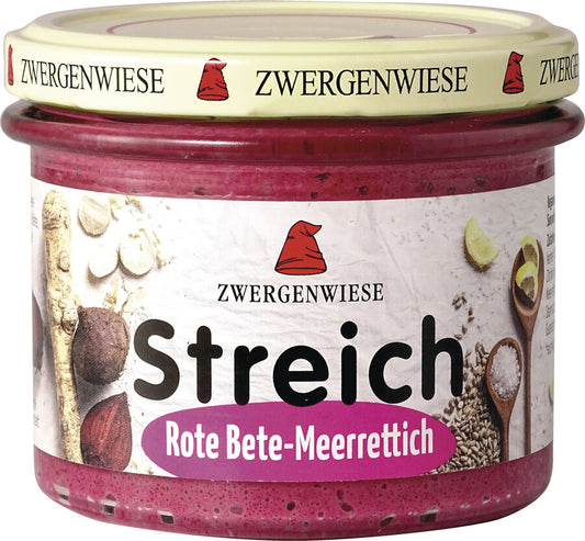 Das Bild zeigt ein Glas des veganen Brotaufstrichs "Streich Rote Bete-Meerrettich" von Zwergenwiese. Der Deckel ist beige mit einem roten Zwergenhut. Das Etikett ist weiß mit Abbildungen von Roter Bete, Meerrettich und Zitronenscheiben. In der Mitte steht "Zwergenwiese Streich Rote Bete-Meerrettich" in schwarzer und pinker Schrift.