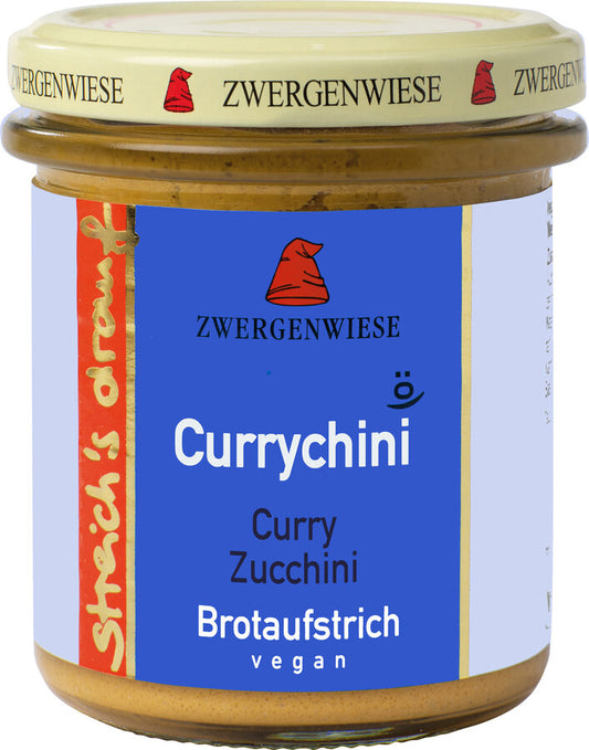 Das Bild zeigt ein Glas "Currychini" Brotaufstrich von Zwergenwiese. Der Deckel ist beige mit einem roten Zwergenhut. Das Etikett ist blau und zeigt die Aufschrift "Zwergenwiese Currychini" in weißer Schrift. Darunter steht "Curry Zucchini". An der Seite des Etiketts steht "Streich's drauf" in gelber Schrift auf rotem Hintergrund. Der Brotaufstrich ist vegan.