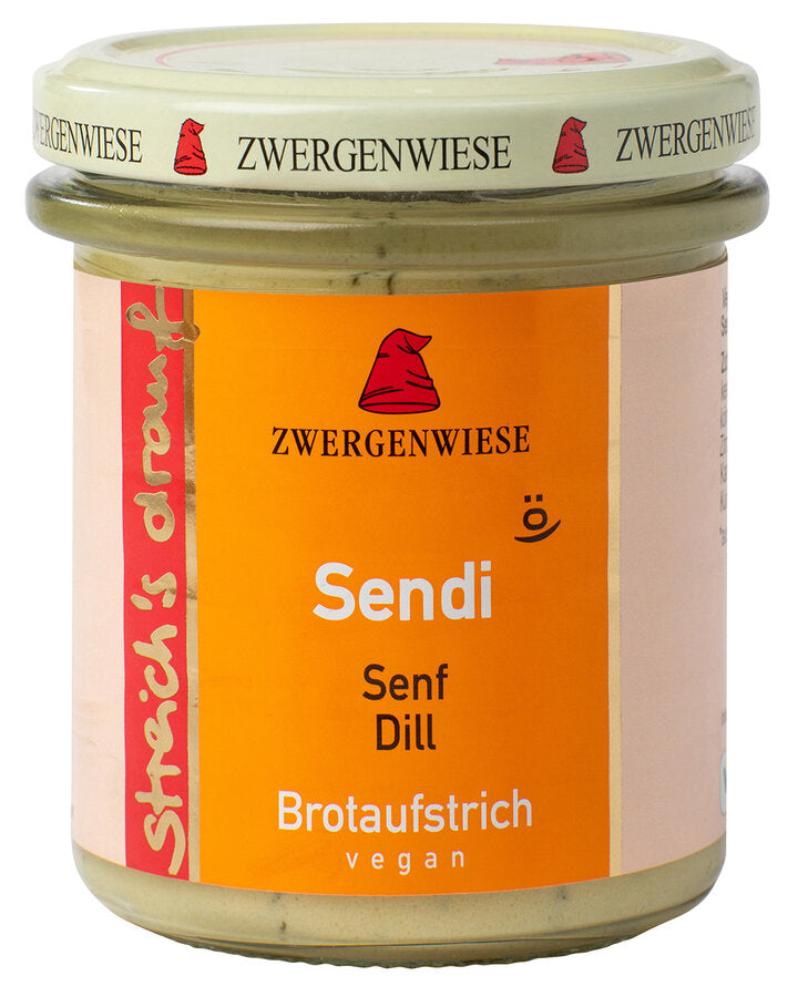 Das Bild zeigt ein Glas "Sendi" Brotaufstrich von Zwergenwiese. Der Deckel ist beige mit roten Zwergenhüten. Das Etikett ist orange und zeigt die Aufschrift "Zwergenwiese Sendi" in weißer Schrift. Darunter steht "Senf Dill". An der Seite des Etiketts steht "Streich's drauf" in gelber Schrift auf rotem Hintergrund. Der Brotaufstrich ist vegan.