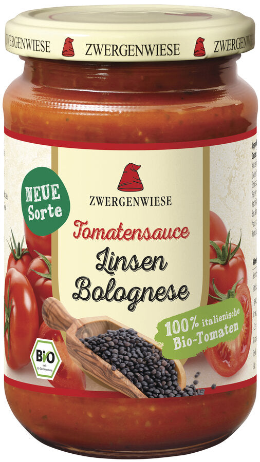 Ein Glas mit der neuen Bio-Tomatensauce Linsen Bolognese von der Marke Zwergenwiese. Das Etikett zeigt eine rote Zwergenmütze und die Aufschrift "Tomatensauce Linsen Bolognese - 100% italienische Bio-Tomaten". Abgebildet sind frische Tomaten und schwarze Linsen, die die reichhaltige und nahrhafte Qualität der Sauce unterstreichen. Der beige Deckel trägt mehrfach das Zwergenwiese-Logo.