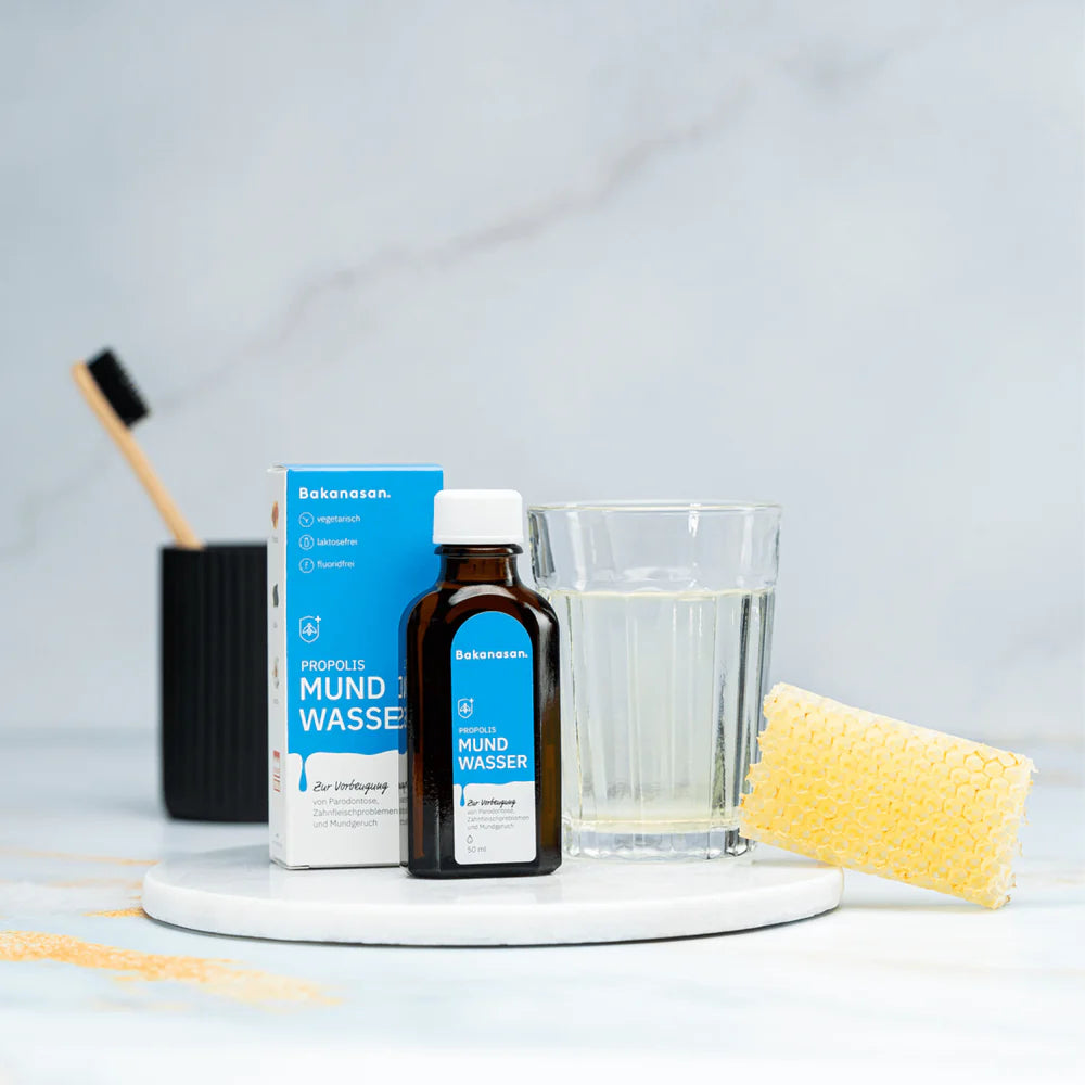 Propolis Mundwasser von Bakanasan mit Glas zur Anwendung auf hellem Marmoruntergrund