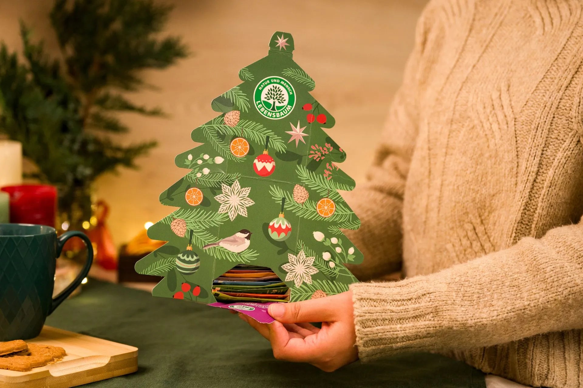 Lebensbaum Tee Adventskalender in Tannenbaumform, festlich dekoriert und von Hand gehalten