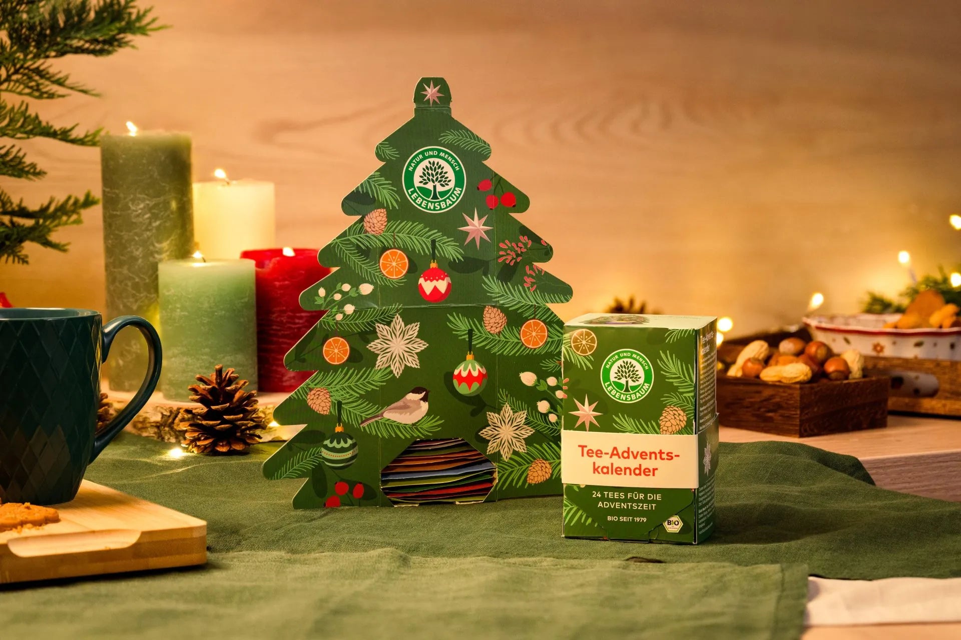 Lebensbaum Tee Adventskalender mit Bio-Packung in weihnachtlicher Szenerie mit Kerzen und Nüssen