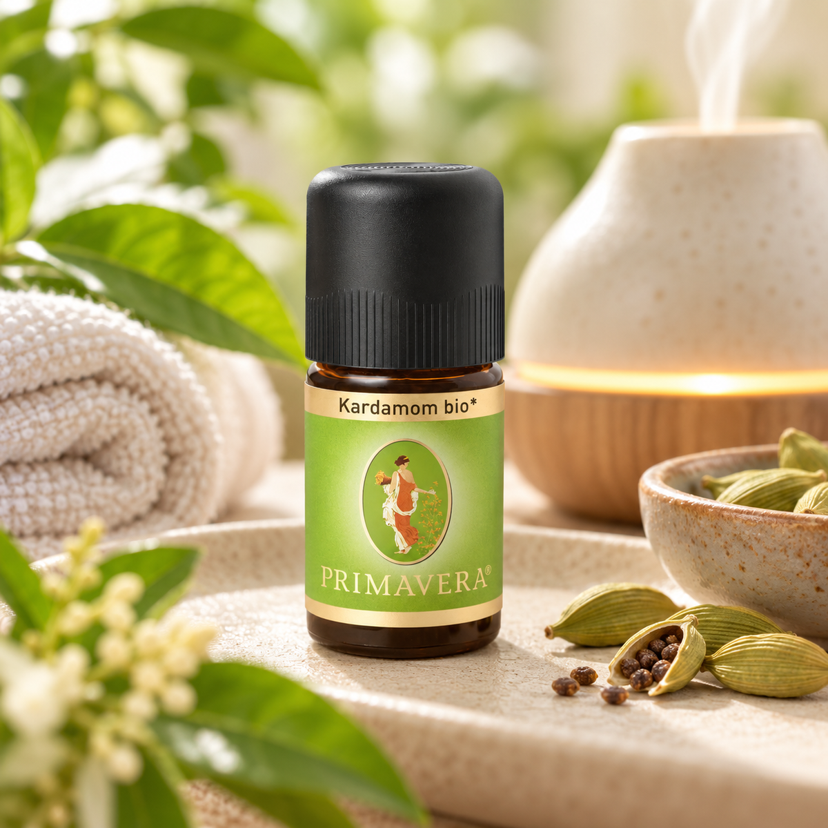 PRIMAVERA Kardamom bio ätherisches Öl neben Aroma-Diffuser und Kardamomkapseln