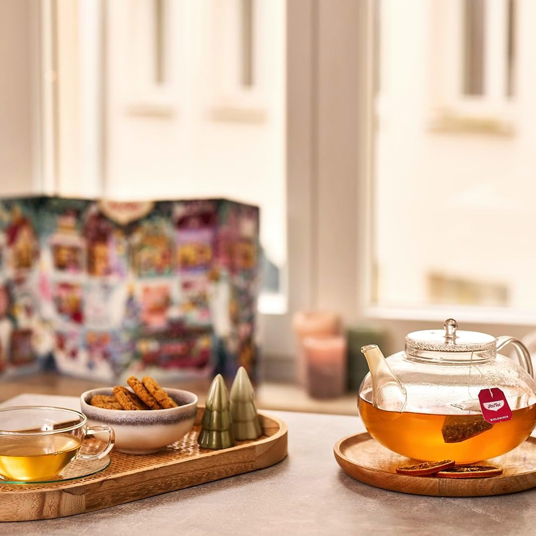 Yogi Tea Adventskalender 2025 auf einem Tisch neben Teekanne, Tasse und Weihnachtsgebäck
